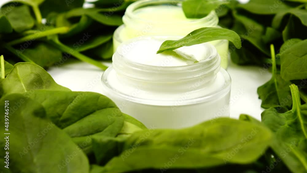 Jars with a skincare product based on spinach is among a heap of the fresh spinach leaves Jars with a skincare product based on spinach is among a heap of the fresh spinach leaves