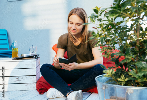 Young woman sitting on patio and using phone photo