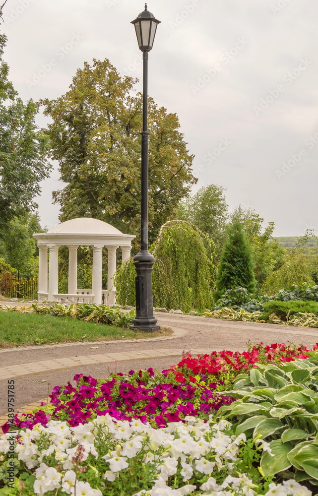 Obraz premium Park with a flower garden, a lantern and an old gazebo-rotunda