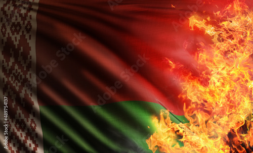 3D composite illustration depicting the national flag of the Republic of Belarus inherited from the soviet union threatened and burnt by the flames of a despotic war or due to global warming wildfires photo