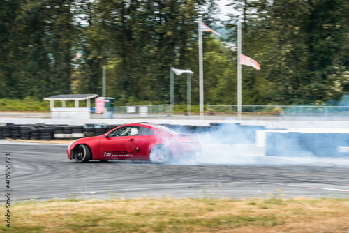 Red Drift Car / Race car drifting around corner very fast with lots of smoke from burning tires on speedway / racetrack / drift track. Infiniti g35 v8. JDM car. Luxury red sport car. 