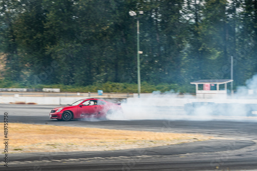 Red Drift Car   Race car drifting around corner very fast with lots of smoke from burning tires on speedway   racetrack   drift track. Infiniti g35 v8. JDM car. Luxury red sport car. 