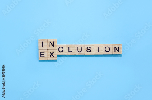 Word inclusion and exclusion on wooden blocks on blue background. Business concept D&I