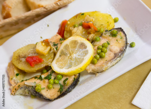 Appetizing baked salmon fillet with baked potatoes, sliced lemon and peas
