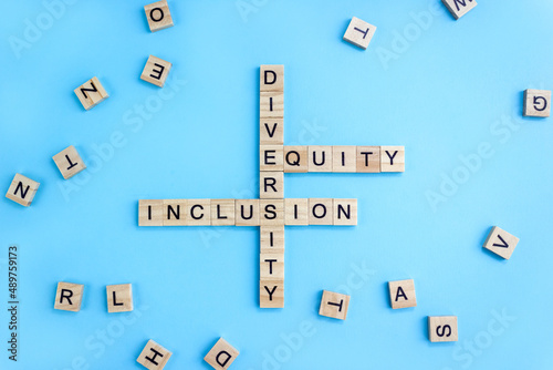 Word Diversity, Equty and Inclusion on wooden blocks on blue background. Business concept DEI photo