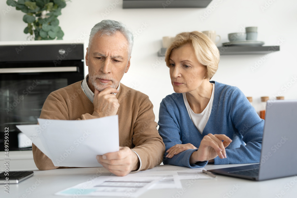 Elderly married couple looking at documents carefully Elderly married couple looking at documents carefully