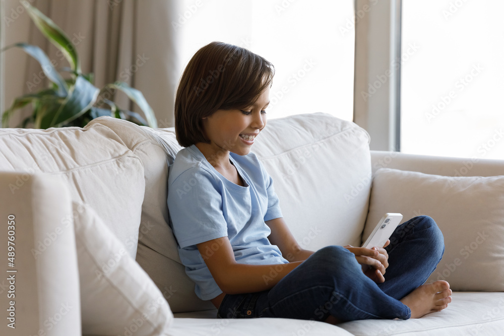 Pretty boy sit on sofa look at cellphone screen smile enjoy new video vlog content, download cool video game, spend leisure at home. Young gen Z using modern tech, parental control software concept Pretty boy sit on sofa look at cellphone screen smile enjoy new video vlog content, download cool video game, spend leisure at home. Young gen Z using modern tech, parental control software concept