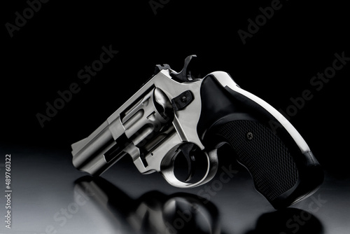 Silver gun revolver on a dark back. Pistol. Weapons for self-defense and sports. photo