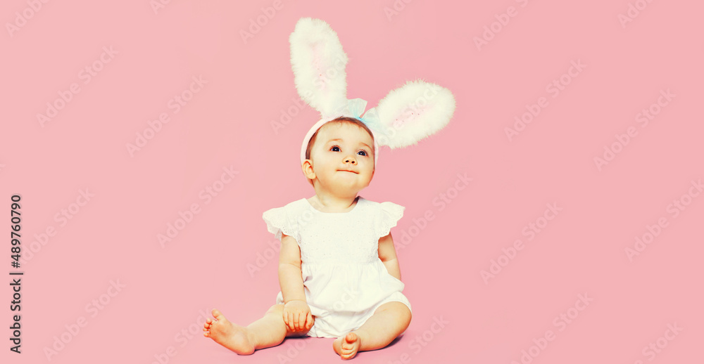 Portrait of cute baby with rabbit ears on pink background