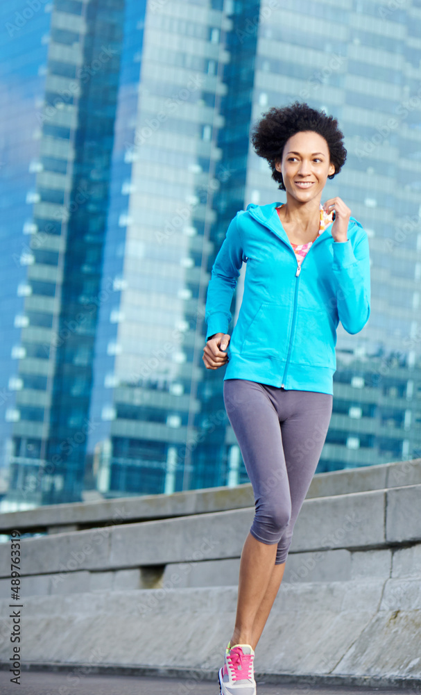 Enjoying an invigorating run. Shot of a young woman jogging through the city.