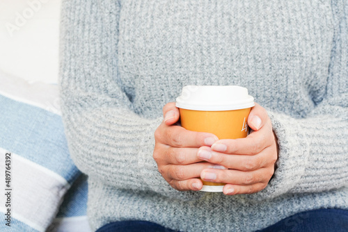winter morning concept woman holding a cup of hot coffee Close-up photo of hands in a warm sweater. with a cup of coffee in hand