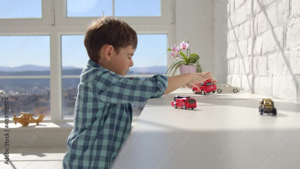 7-8 years old boy playing with little cars alone in his house. Asocial child concept. 4k slow motion 7-8 years old boy playing with little cars alone in his house. Asocial child concept. 4k slow motion