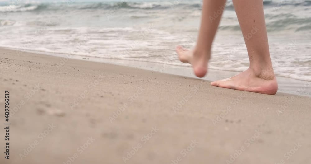 Along the coastline with bare feet. A girl with bare feet enjoy walking along the sea in the waves. Along the coastline with bare feet. A girl with bare feet enjoy walking along the sea in the waves.