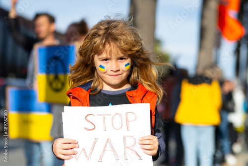 Child boy with poster with banner of russia conflict, military protest. America stand with Ukraine. Child with message Stop War. No war with Ukraine. photo