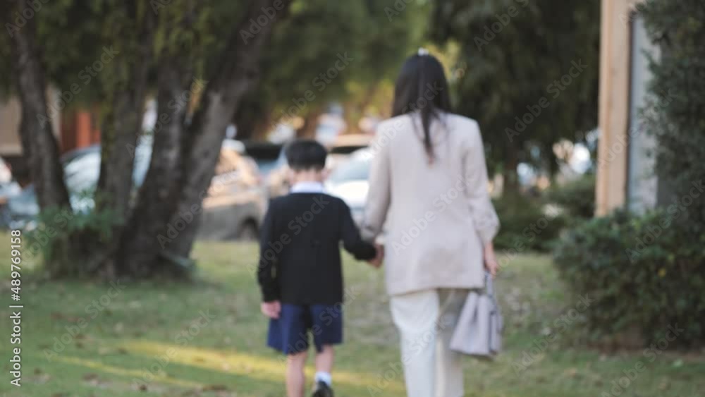 Asian boy walking while holding his mother's hand. A 6 years old kid with a face mask goes to pre-elementary school. Asian boy walking while holding his mother's hand. A 6 years old kid with a face mask goes to pre-elementary school.