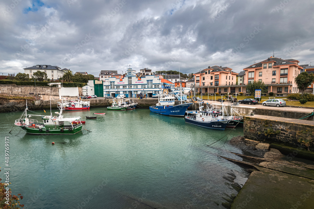 Picturesque port area of Puerto de Vega town in Asturias, Spain with beautiful blue waters and fishing boats.
