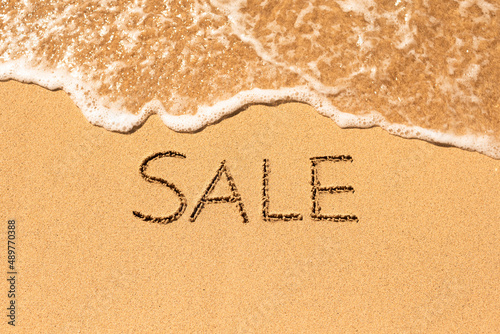 Sale word written on sandy beach. Summer beach vacation sale concept. 
