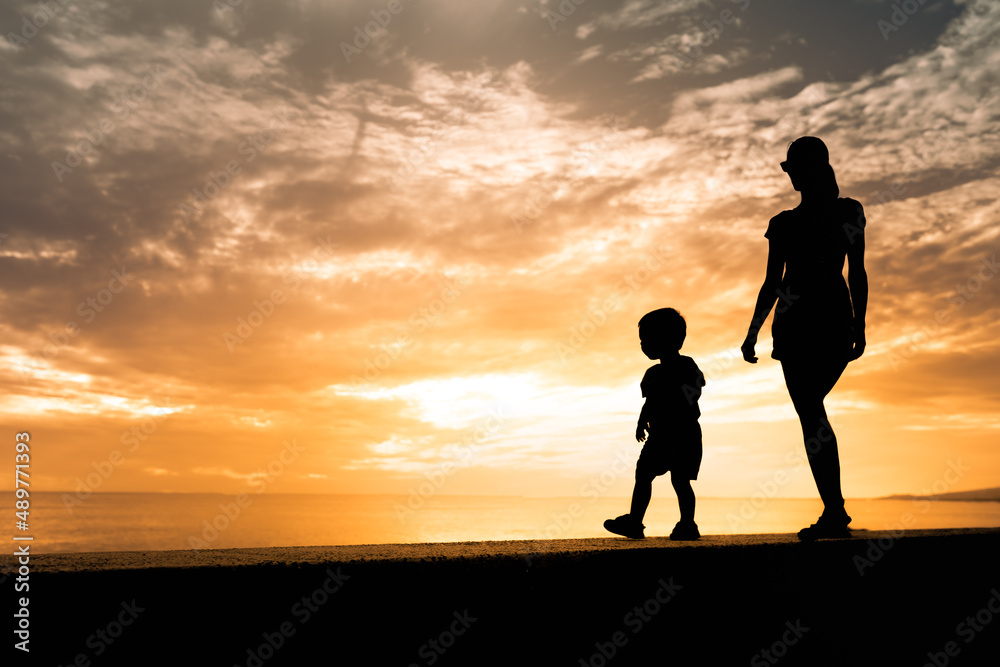 Mother and child walking together at sunset 