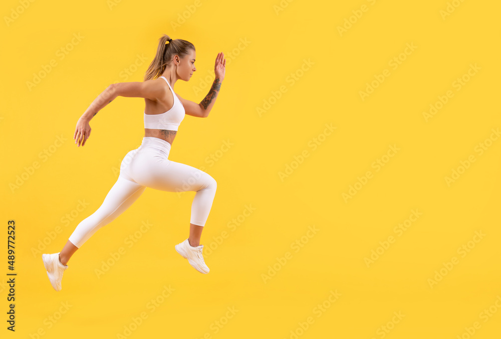 fitness woman runner running on yellow background. copy space