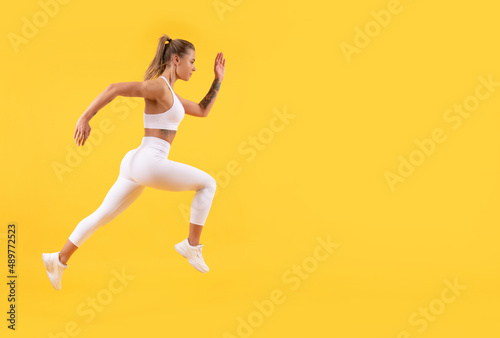 fitness woman runner running on yellow background. copy space