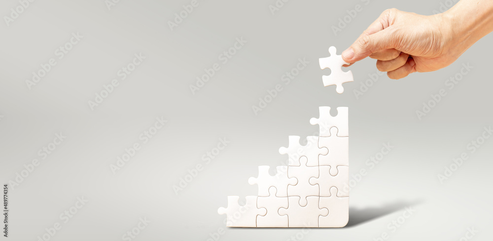Step by Step to Build Up Future with your own hands concept, Hand fill  white jigsaw puzzle to fulfill the puzzle Photos | Adobe Stock