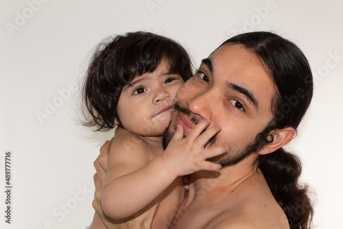 portrait of a hispanic father and son playing and smiling on a white background