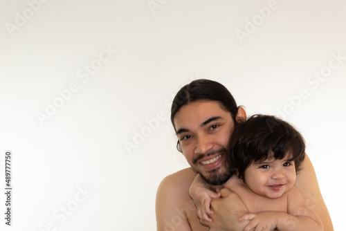 portrait of a hispanic father and son hugging on a white background