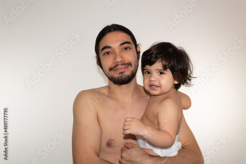 portrait of a hispanic father and son hugging on a white background