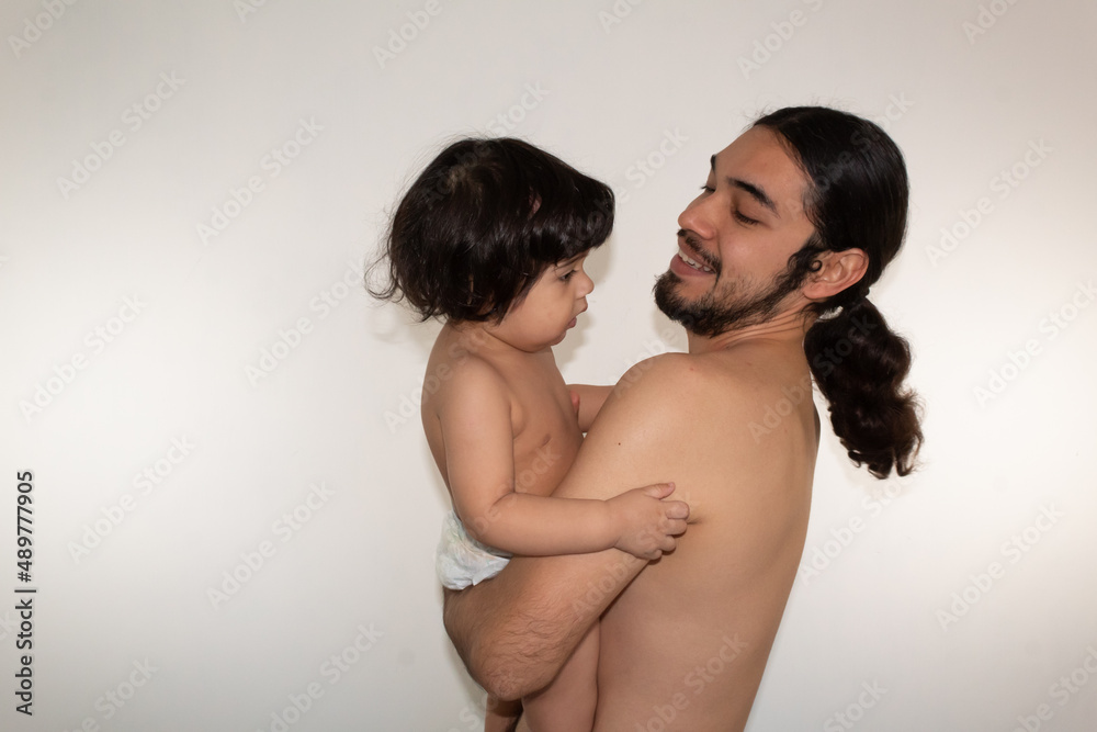 portrait of a hispanic father and son hugging on a white background portrait of a hispanic father and son hugging on a white background