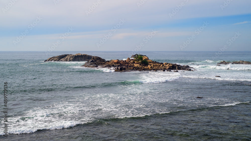 Small rocky island formation in the Indian ocean, Scenic seascape photograph high angle view.