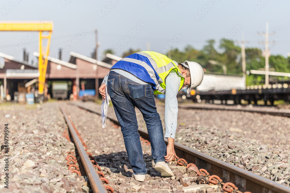 Engineer under inspection and checking construction process railway locomotive repair plant, Engineer man in waistcoats and hardhats and with documents in a railway depot Engineer under inspection and checking construction process railway locomotive repair plant, Engineer man in waistcoats and hardhats and with documents in a railway depot