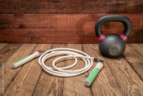 Canvastavla heavy fitness jump rope and iron kettlebell on rustic, weathered wood background