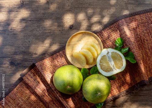 pamelo on a wooden plate with natural light on a wooden table in a garden photo