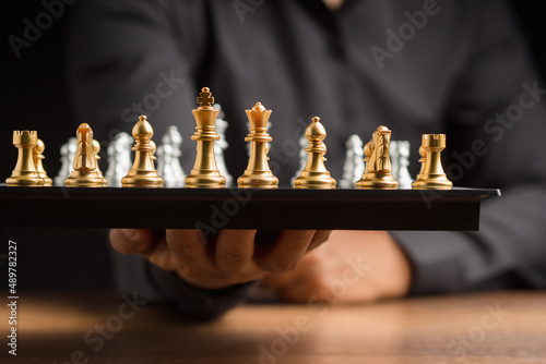 Businessman in a black shirt holding a chessboard. Business strategy ideas and investment