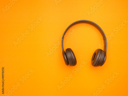 Top view of a black headphones on orange background
