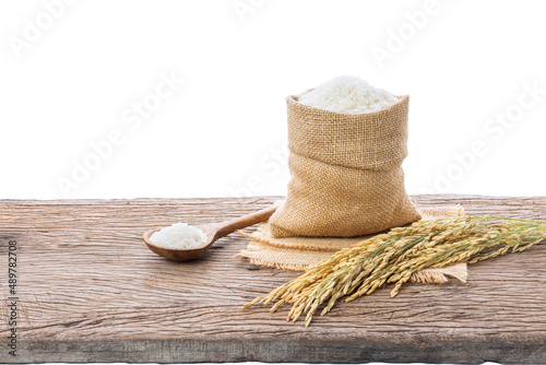 Organic white rice or jasmine rice in a sack and the ears of rice lying on the wooden floor on a white background