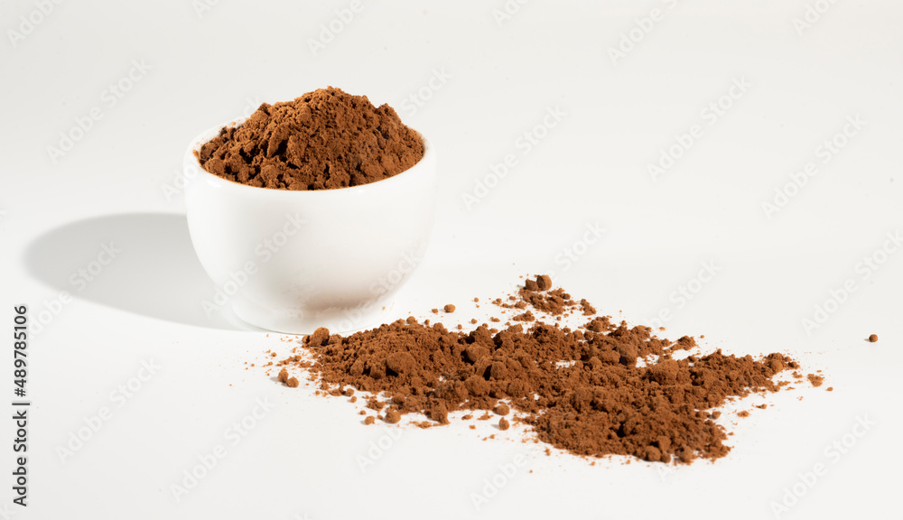 Cocoa powder in white bowl оn white background. Cocoa powder in white bowl оn white background.