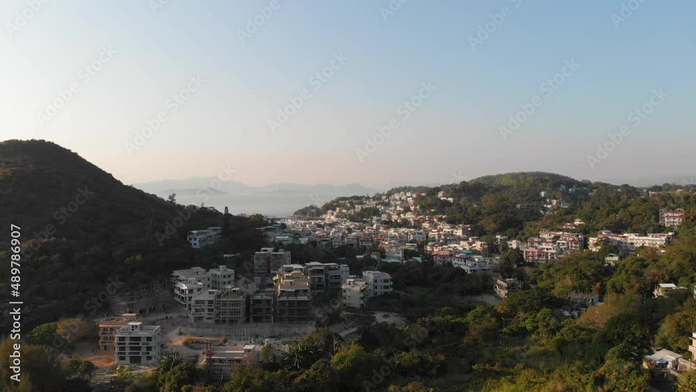 Aerial drone shot of an old and peaceful island in Hong Kong with a clear sky, dense forest and islands in the background Aerial drone shot of an old and peaceful island in Hong Kong with a clear sky, dense forest and islands in the background