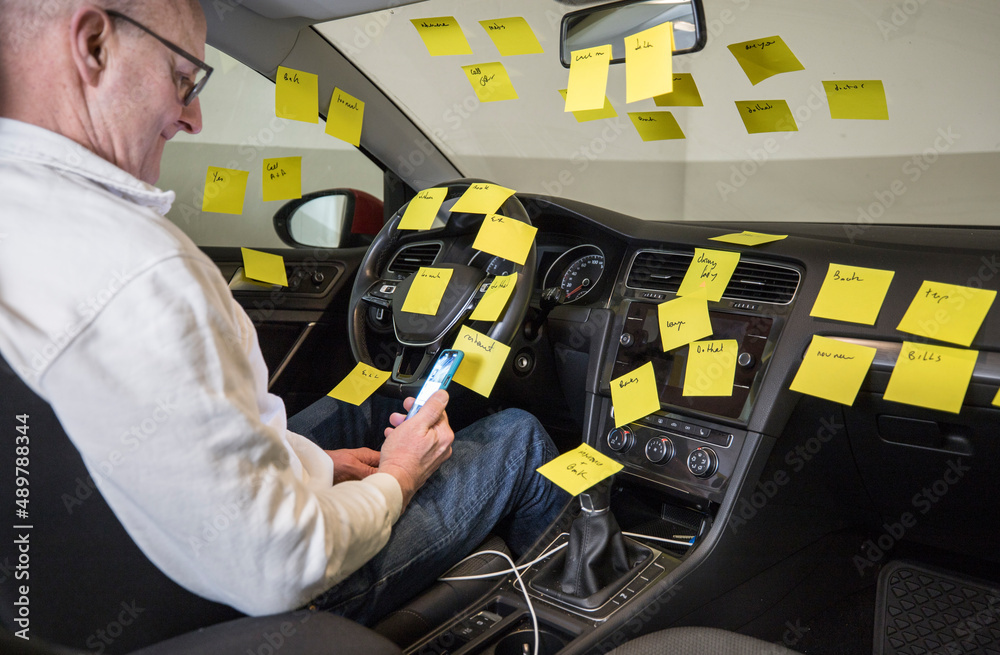 Fototapeta premium A man working in the driver's seat of a car surrounded by many to-do notes.