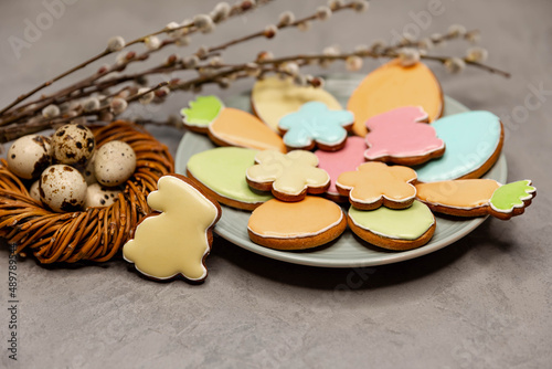 Spring holiday baking concept. Compositin of Easter cookies on grey concrete background. Colourful sugar cookies in shape of Easter eggs, carrots and flowers with decorative icing. photo