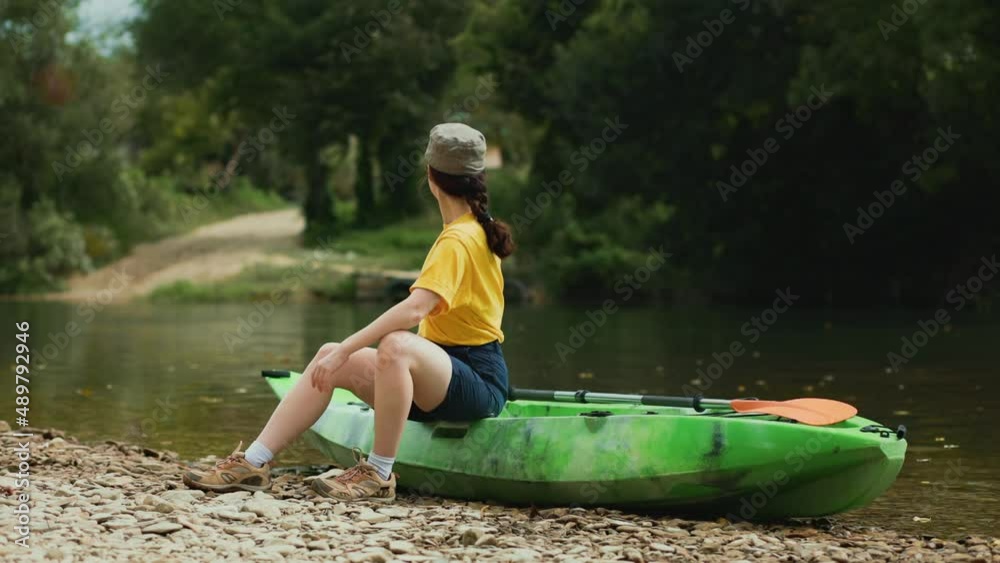 Summertime. A young woman is sitting on a kayak, admiring the landscape. Real time. Camping and tourism concept. Summertime. A young woman is sitting on a kayak, admiring the landscape. Real time. Camping and tourism concept.