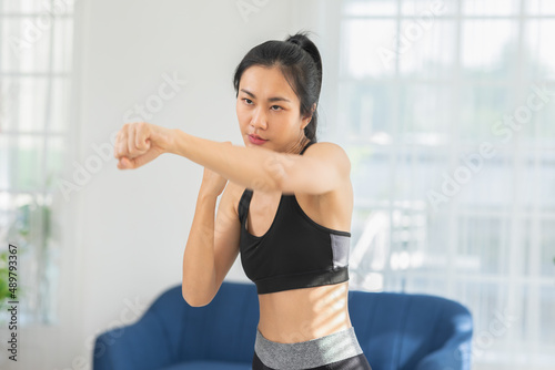 Athletic Healthy Asian young woman in sportswear workout boxing excercise training at home.Young female with slim body punching boxing footwork cardio exercise.healthy lifestyle concept © 220 Selfmade studio