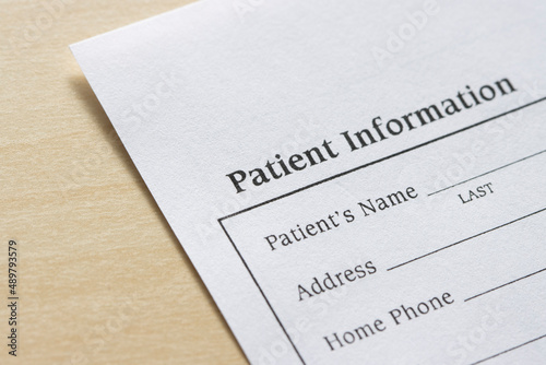 Closeup of a blank patient information form isolated on a wooden background.
