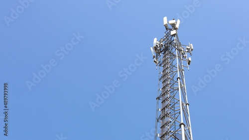 Cellular Base Station Tower. A base station equipped with 4G and 5G cellular wireless communication technology with a mobile phone with a clear sky background with copy space. Selective focus