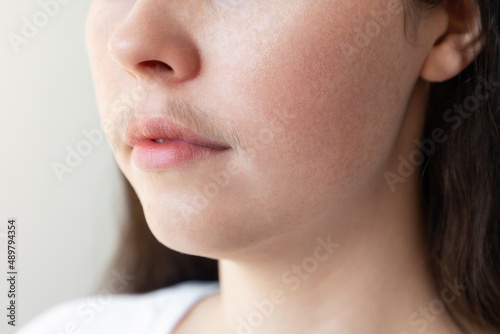 A close-up of a woman's face with a mustache over her upper lip. The concept of hair removal and epilation