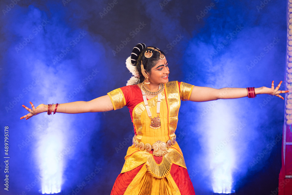 Smiling indian bharatanatyam dancer on stage performing dance with hands gesture - conept of artist, Traditional indian culture and clasic dancer.