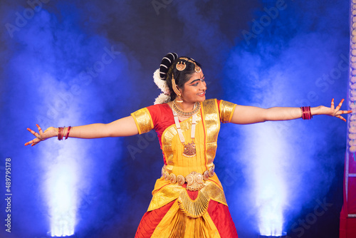 Smiling indian bharatanatyam dancer on stage performing dance with hands gesture - conept of artist, Traditional indian culture and clasic dancer. photo