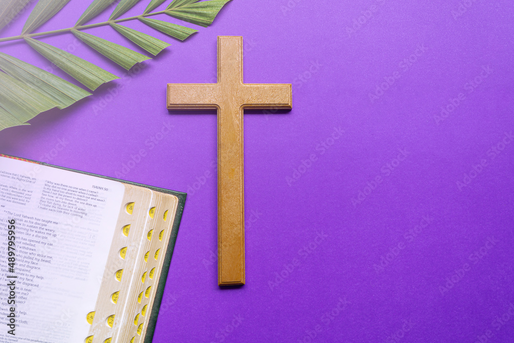 Cross and holy bible with palm leaves on purple background. Holy week concept.