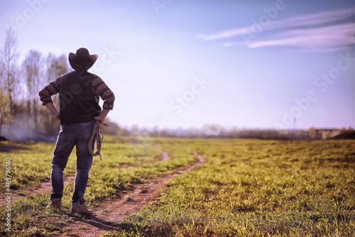 Cowboy standing in a field at sunset