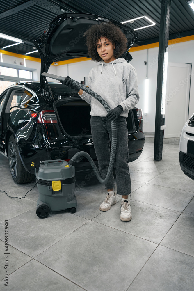Auto detailer standing beside motor vehicle with open trunk Auto detailer standing beside motor vehicle with open trunk